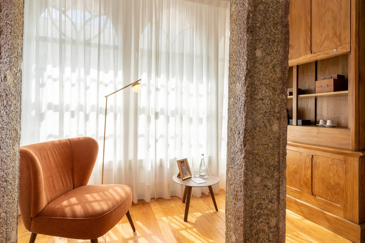 Interior com poltrona, cortinas e paredes de granito